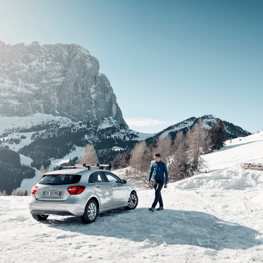 A man is walking towards his car in a snowy landscape
