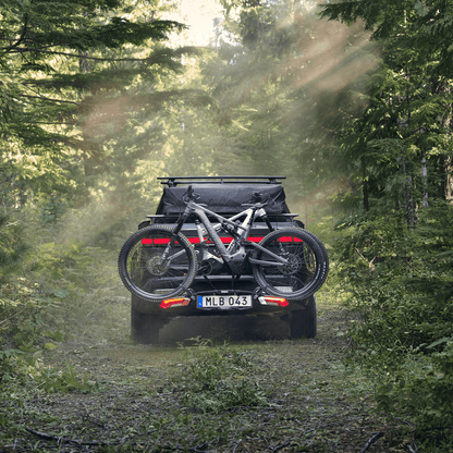 A car with a bike on a bike carrier is parked by a lake.